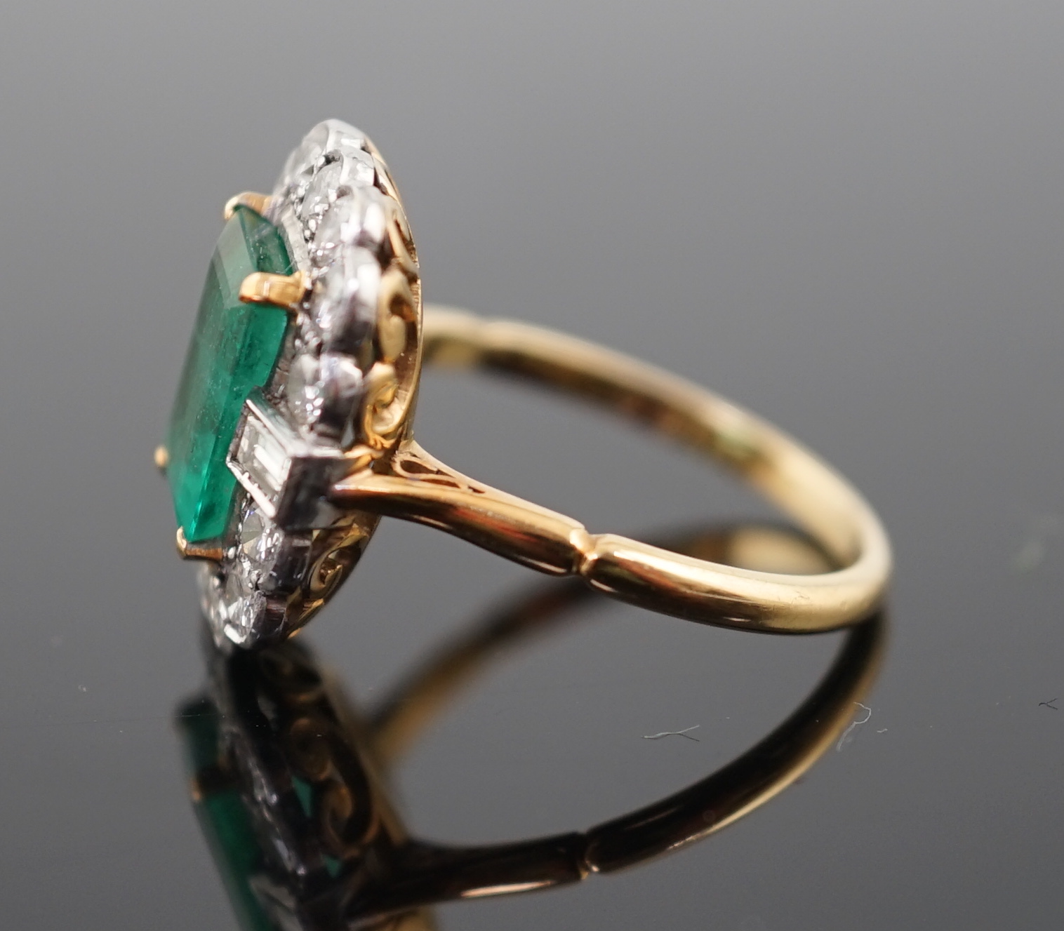 An Art Deco style yellow metal, emerald and diamond set oval cluster ring